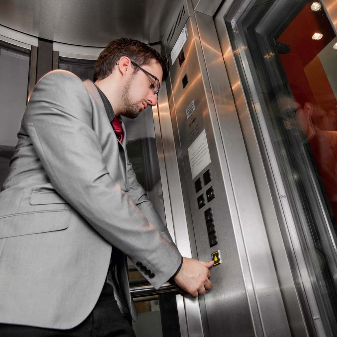 Person betätigt Notruf im Lift